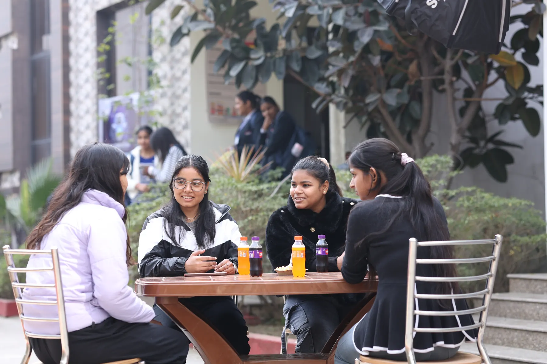 Students chatting over drinks at the outdoor cafeteria