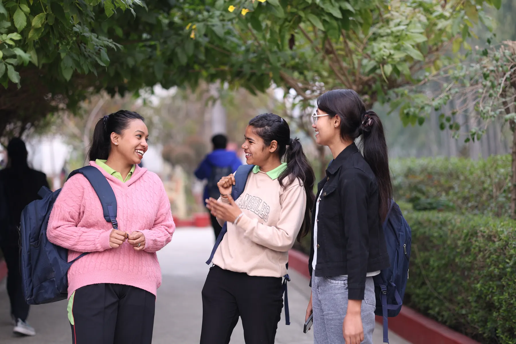 Three students chatting under the trees on campus